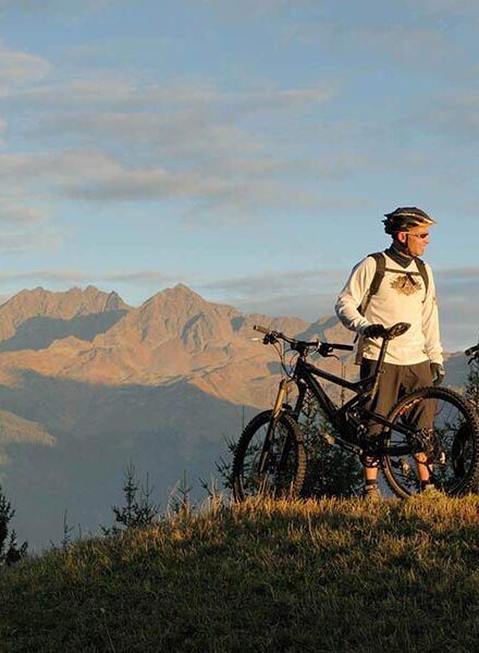 Zwei Männer stehen sich mit ihrem Fahrrad gegenüber und genießen den Blick auf die Alpen