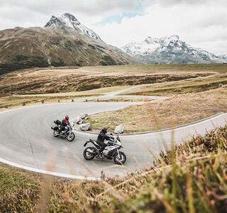 Two motorcyclists are riding a winding road.