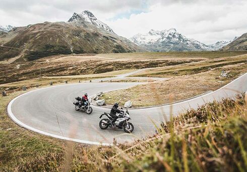 Two motorcyclists are riding a winding road.