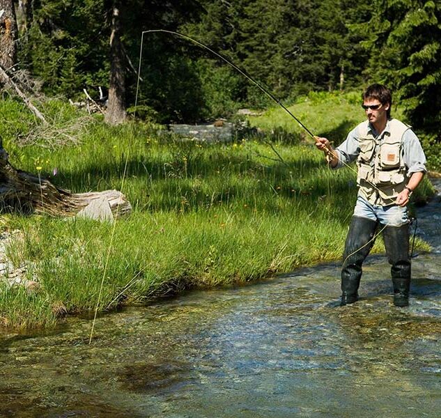 A man fishes in clear mountain waters