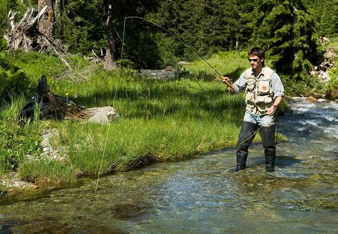 A man fishes in clear mountain waters