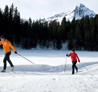 A couple cross-country skiing on a freshly prepared trail.