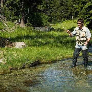 A man fishes in clear mountain waters