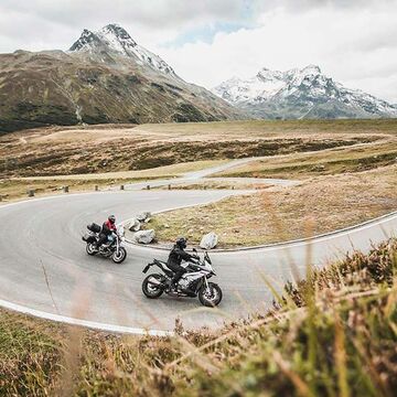 Two motorcyclists are riding a winding road.