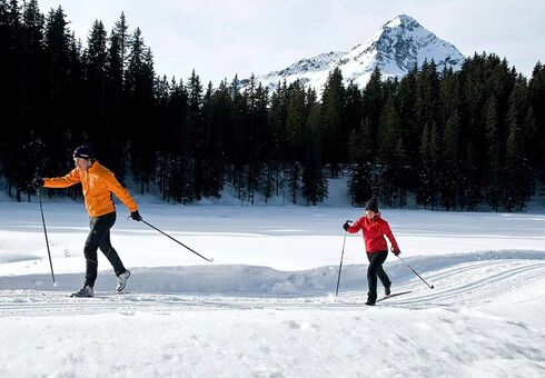 A couple cross-country skiing on a freshly prepared trail.