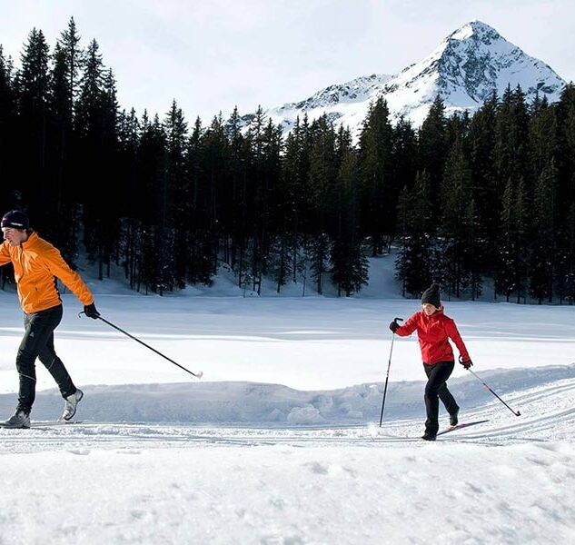 A couple cross-country skiing on a freshly prepared trail.