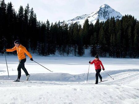 Ein Paar beim Skilanglauf auf einer frisch präperierten Loipe