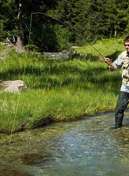 A man fishes in clear mountain waters