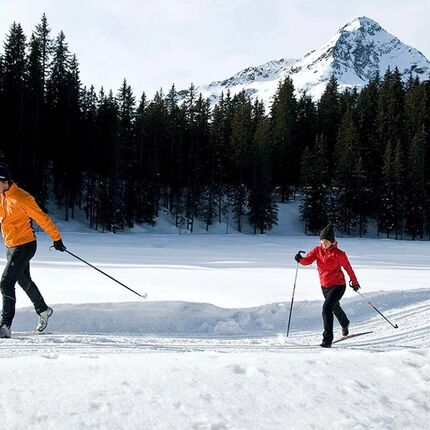 A couple cross-country skiing on a freshly prepared trail.