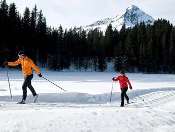 Ein Paar beim Skilanglauf auf einer frisch präperierten Loipe